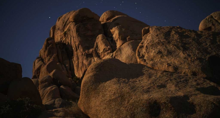 Large boulders appear in front of a dark blue, starry sky.